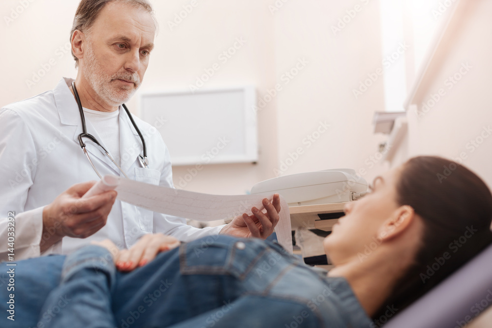 Fototapeta premium Supporting mature specialist describing the results of patients tests