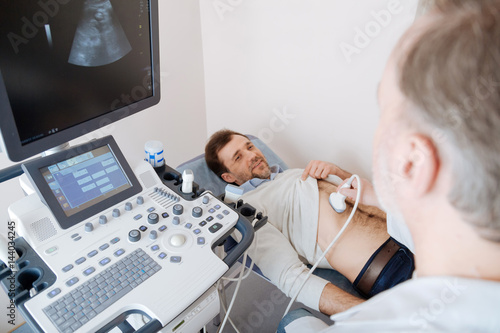 Fotografía Methodical determined doctor scanning young mans organs