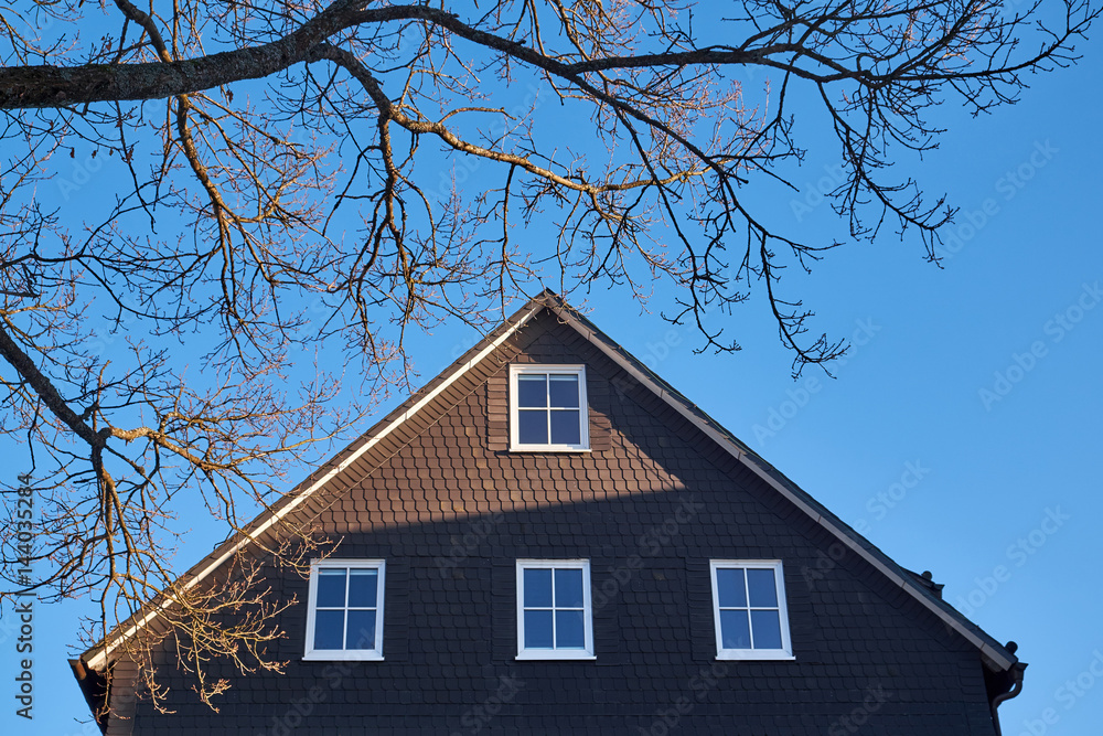 Traditional slate slab cladded house gable with white windows in Winterberg Germany Traditional slate slab cladded house gable with white windows in Winterberg Germany