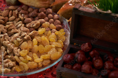 Large collection of nuts, seeds and dried fruits in brown wooden bowls isolated on a golden background