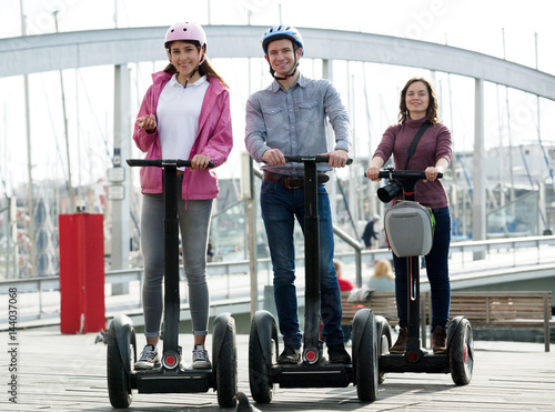 Girls and guy traveling through city by segways photo