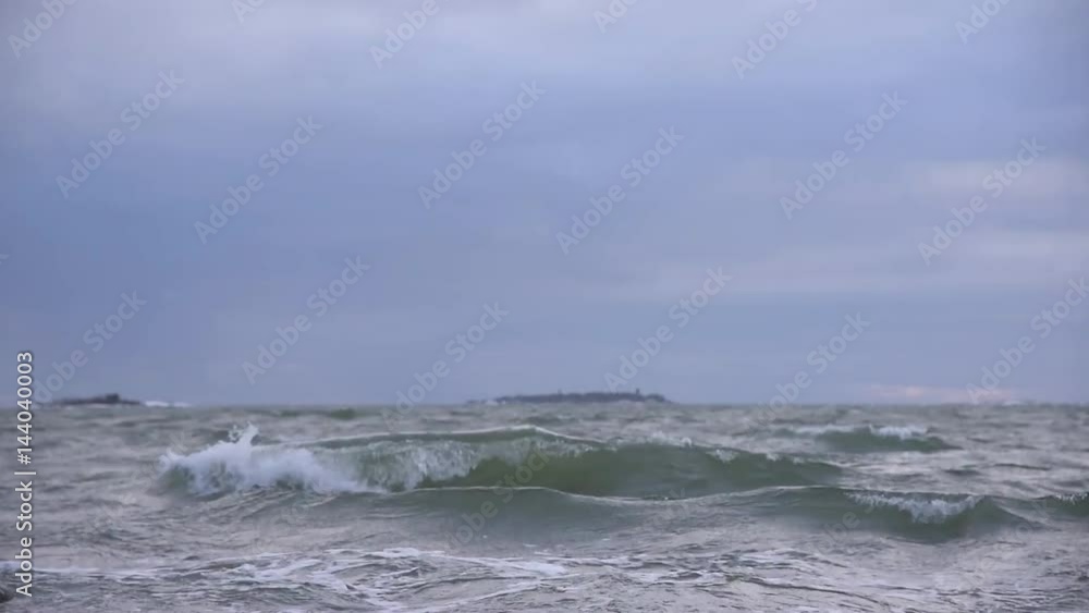 Waves bounding into shore in the Baltic Sea in Helsinki archipelago in Finland on early January stormy and cloudy afternoon. Weather is extremely windy. Waves bounding into shore in the Baltic Sea in Helsinki archipelago in Finland on early January stormy and cloudy afternoon. Weather is extremely windy.