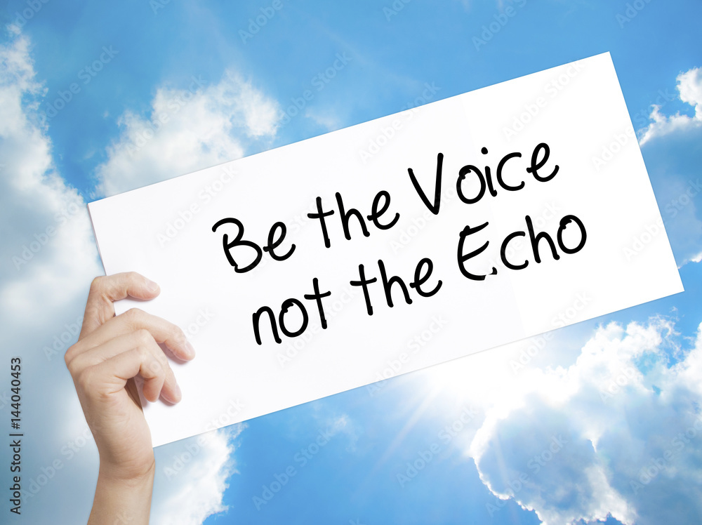 Be the Voice not the Echo Sign on white paper. Man Hand Holding Paper with text. Isolated on sky background. Be the Voice not the Echo Sign on white paper. Man Hand Holding Paper with text. Isolated on sky background.
