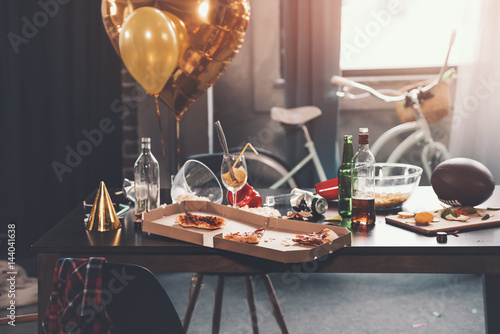 Photography Messy table with pizza in box and beverages at morning after party