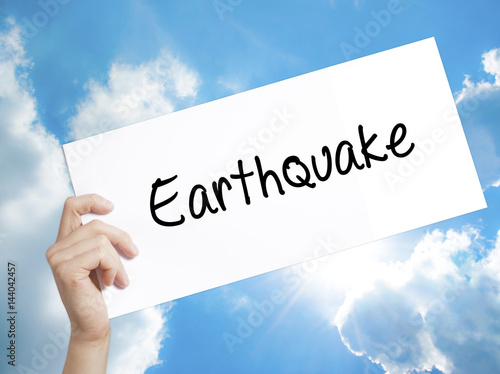 Earthquake Sign on white paper. Man Hand Holding Paper with text. Isolated on sky background photo