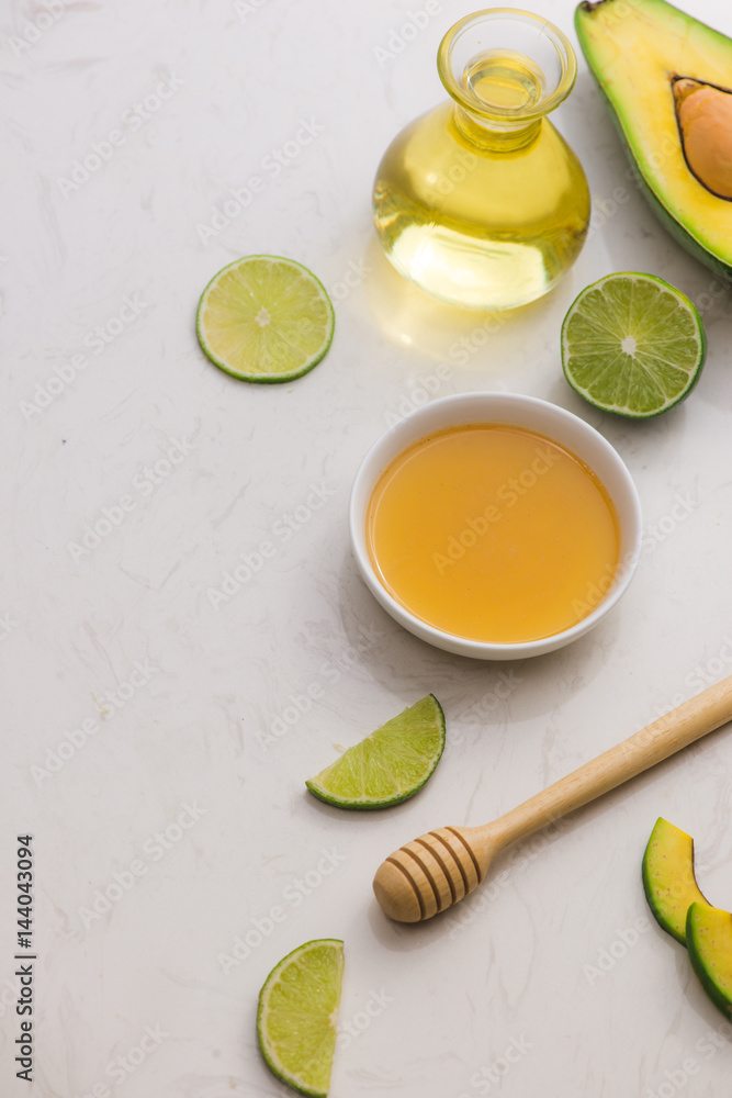 Healthy food concept. Fresh organic avocado oil and lime with honey on table Healthy food concept. Fresh organic avocado oil and lime with honey on table