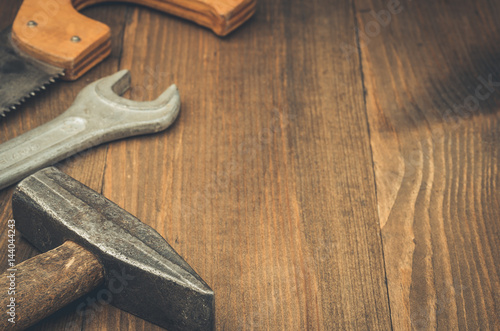 building background on a wooden surface/construction tools a wrench, hammer and a saw