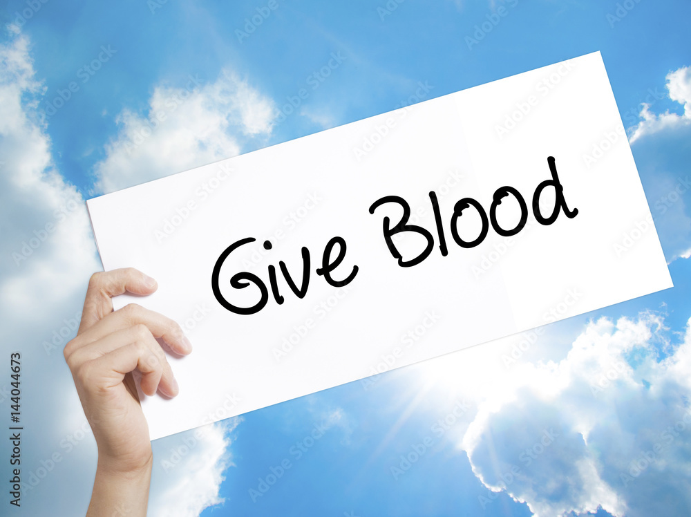 Give Blood Sign on white paper. Man Hand Holding Paper with text. Isolated on sky background Give Blood Sign on white paper. Man Hand Holding Paper with text. Isolated on sky background