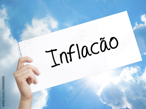 Infacao (Inflation in Portuguese) Sign on white paper. Man Hand Holding Paper with text. Isolated on sky background