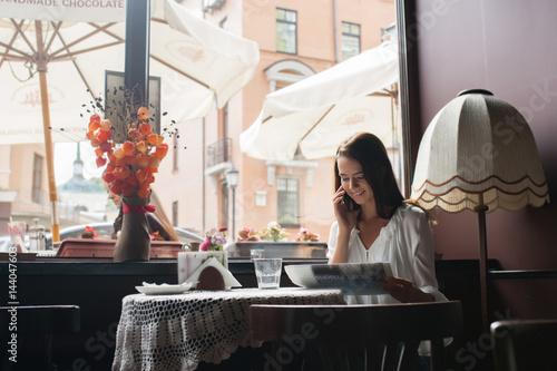 Pretty girl having cup of coffee and reading newspaper
