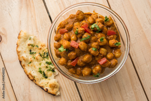 spicy chick peas curry or Chola Masala or Chana Masala or chole bhature or choley garnished with sliced onion and green coriander leaf, selective focus