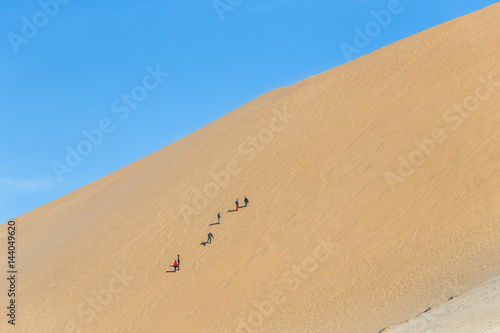 Tourists climb thethe Dune #7 in Sossusvlei plato of Namib Naukluft National Park - Namibia, South Africa photo