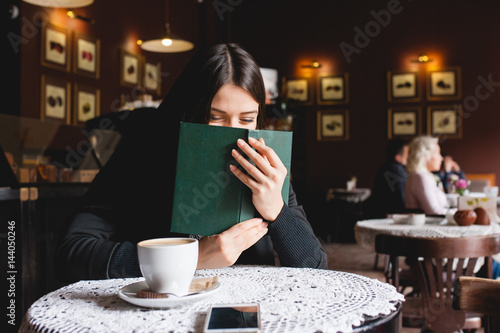 Portrait of a beautiful girl reading book in cafe