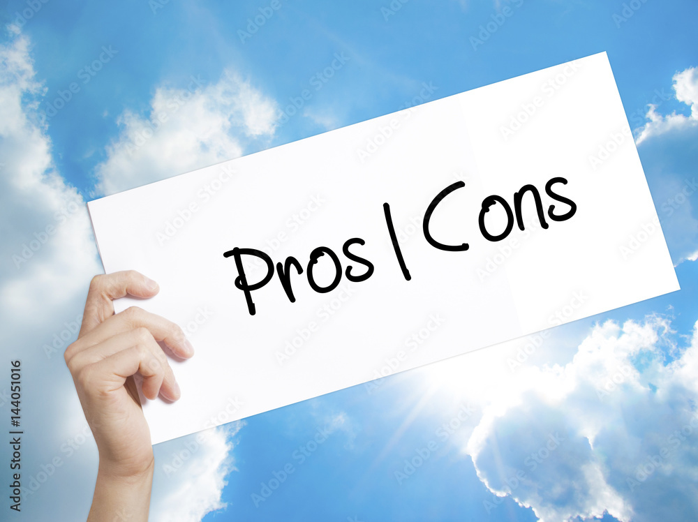 Pros Cons Sign on white paper. Man Hand Holding Paper with text. Isolated on sky background Pros Cons Sign on white paper. Man Hand Holding Paper with text. Isolated on sky background