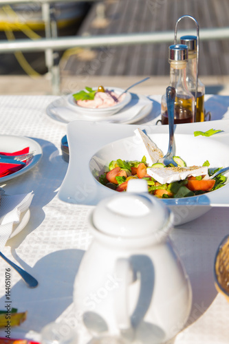 Greek salad or Fresh tasty vegetable salad with white feta cheese on the table in Restaurant on a beach.