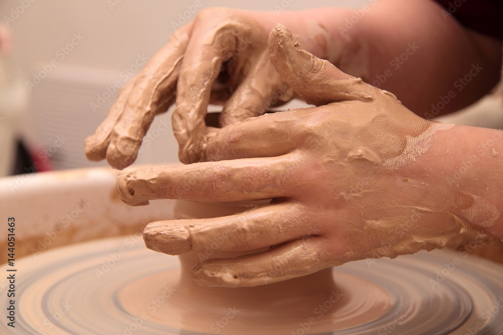 Hands of a potter, creating an earthen jar on pottery wheel. Hands of a potter, creating an earthen jar on pottery wheel.