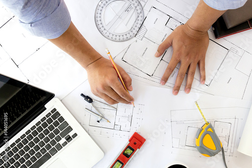 Interior designer discussing data and digital tablet and computer laptop with business document and graphics design diagram on wooden desk as concept