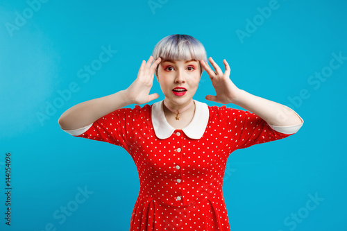 Picture of beautiful dollish girl with short light violet hair wearing red dress over blue background. photo