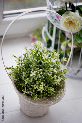 A basket of flowers standing on the windowsill.Wildflowers fine in green and white.