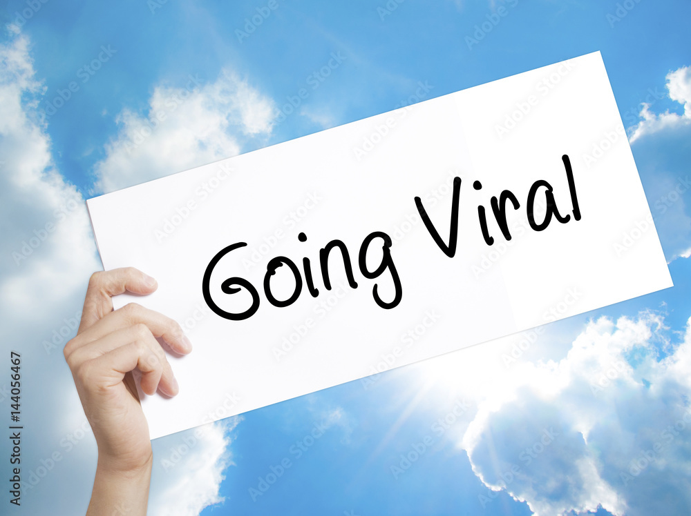 Going Viral Sign on white paper. Man Hand Holding Paper with text. Isolated on sky background Going Viral Sign on white paper. Man Hand Holding Paper with text. Isolated on sky background
