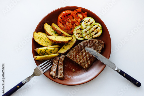 Juicy thick medallion of lean flank beef steak marinated and grilled over a summer BBQ viewed close up from above over white