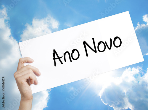 &quot;Ano Novo&quot; (In Portuguese: New Year) Sign on white paper. Man Hand Holding Paper with text. Isolated on sky background