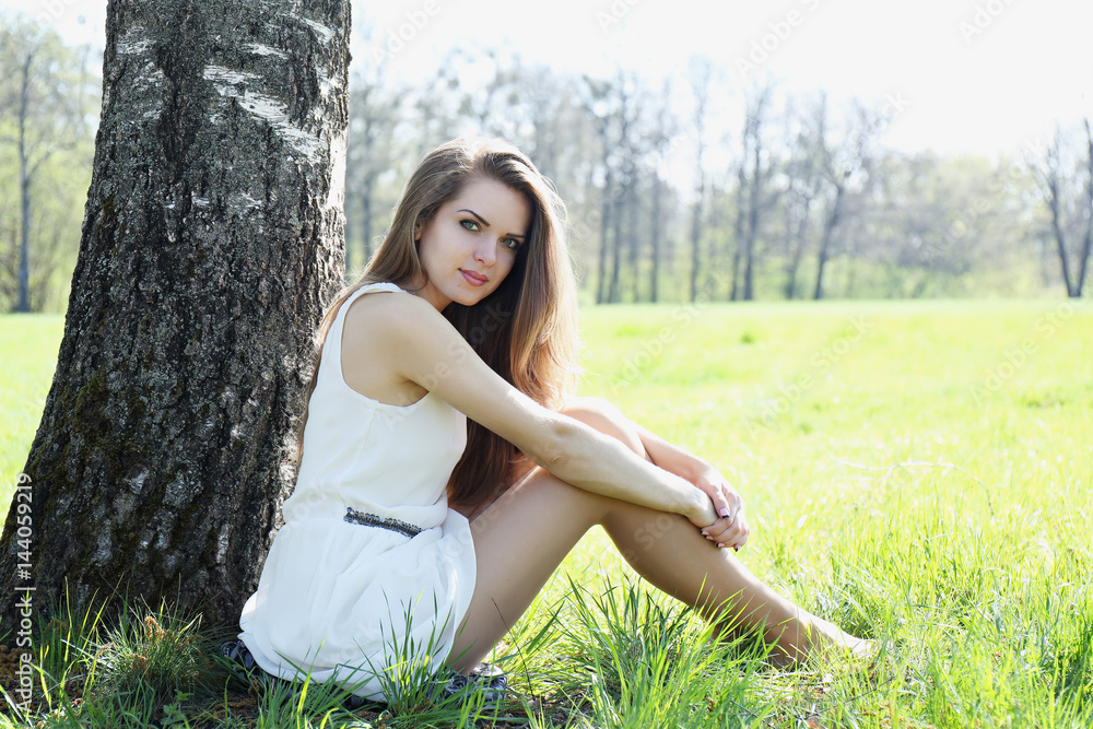 girl sits under the tree in the meadow girl sits under the tree in the meadow