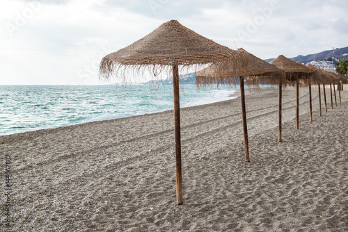 Straw parasols on empty beach. Nerja  Spain