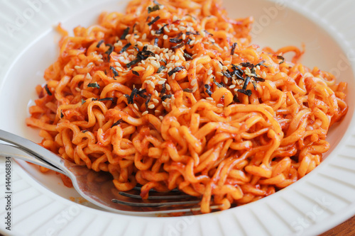 Spicy noodles sprinkle sesame seeds and seaweed on a wooden background.