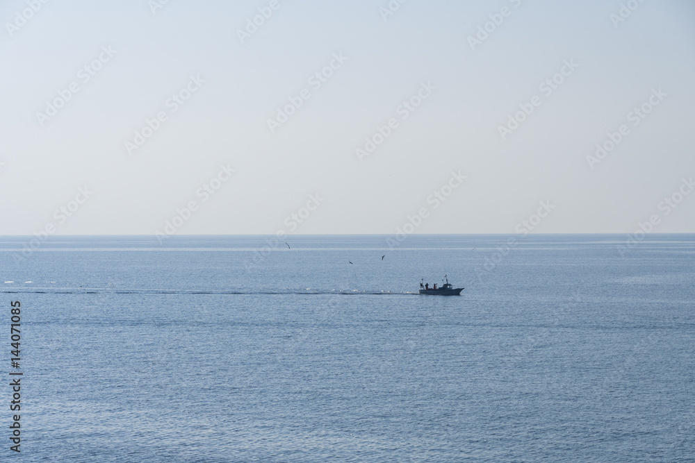 Seascape with small fishing boat sailing on calm sea