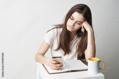 A teenage girl writes a message on the phone. Isolated on white background.