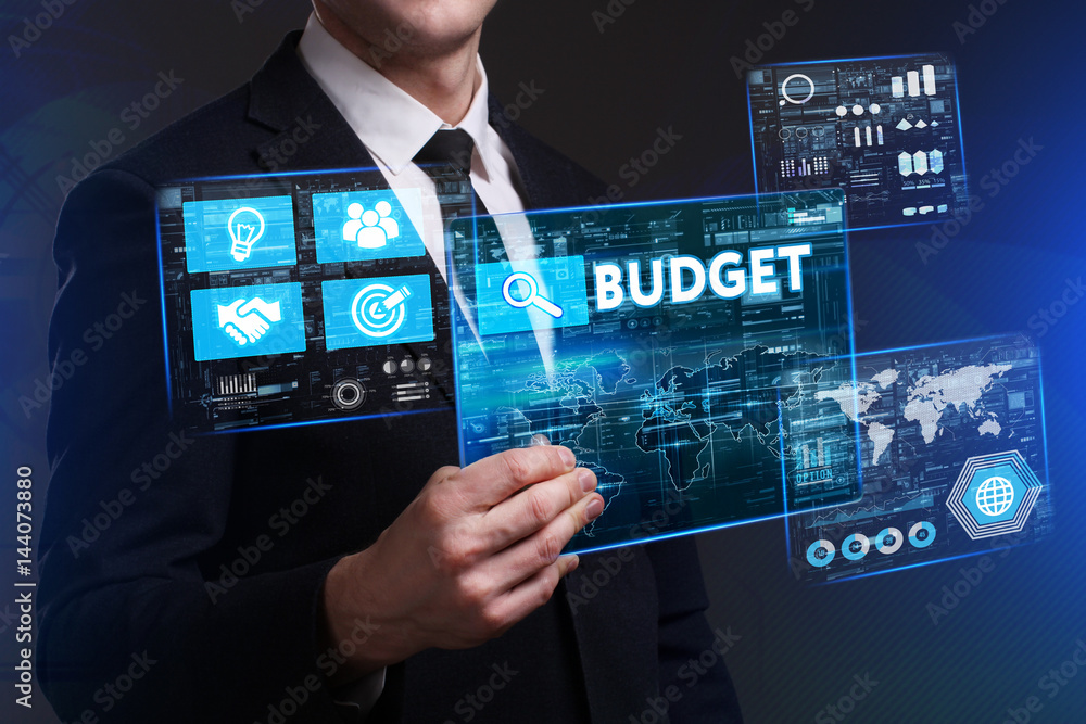 Business, Technology, Internet and network concept. Young businessman working on a virtual screen of the future and sees the inscription: Budget Business, Technology, Internet and network concept. Young businessman working on a virtual screen of the future and sees the inscription: Budget