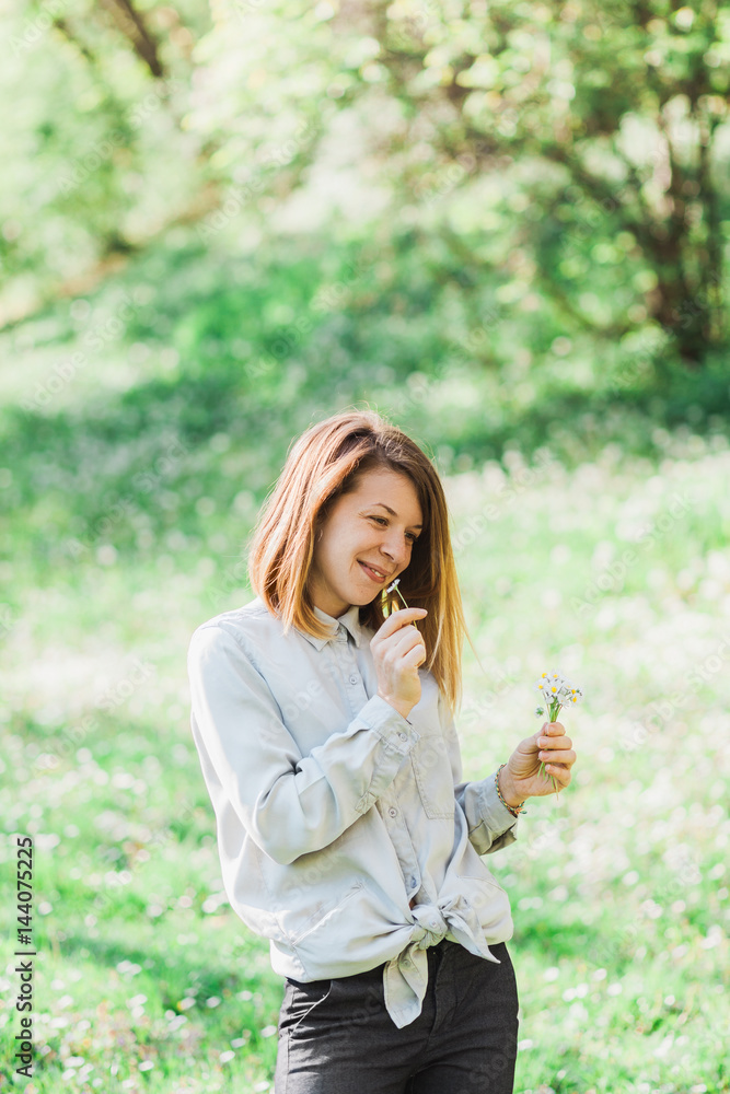 Young woman smelling flowers outside in nature Young woman smelling flowers outside in nature