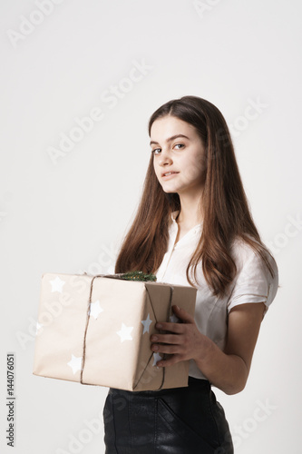 The girl is standing with a gift box. Isolated on white background.