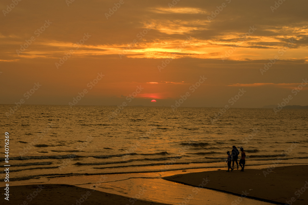 People strolling on the beach at sunset