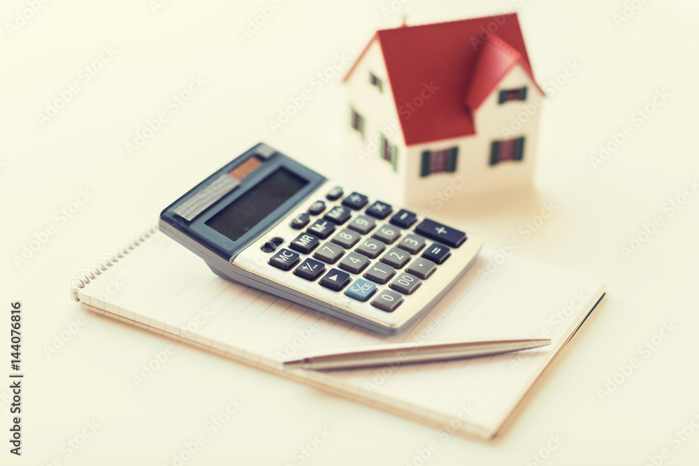 close up of home model, calculator and notebook close up of home model, calculator and notebook