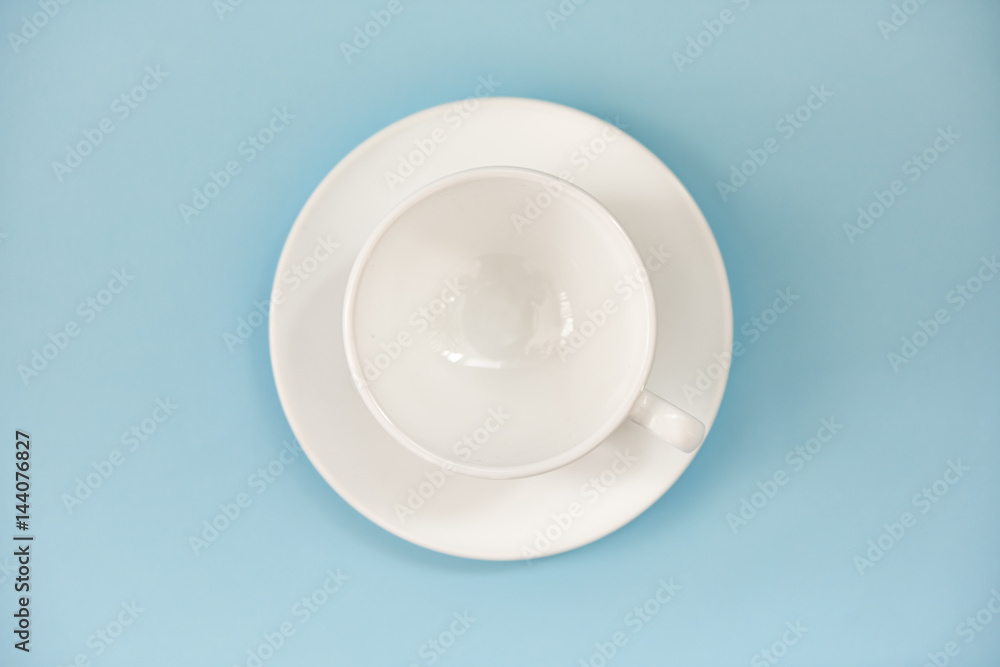Top view of empty white cup with plate over blue background. Top view of empty white cup with plate over blue background.