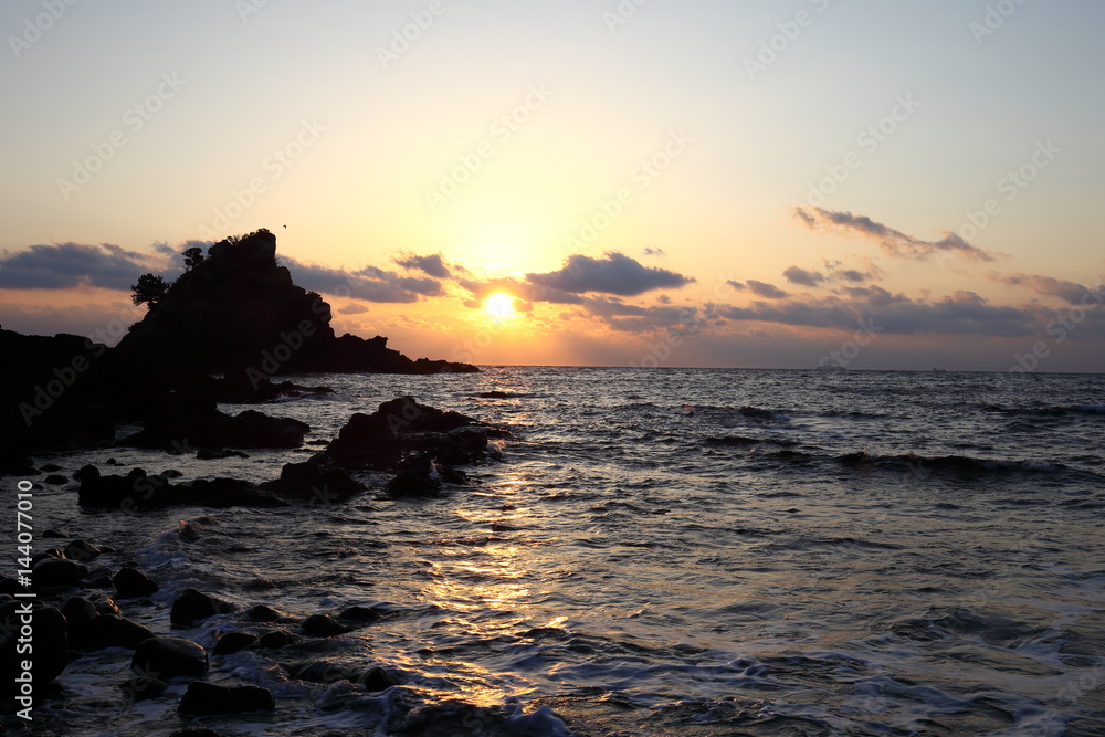 Sunrise and morning light on pacific ocean beach with rocks and water
