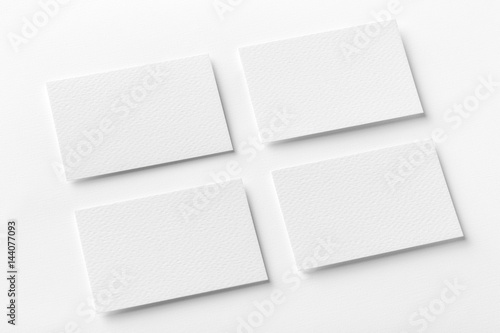 Mockup of four white business cards arranged in rows at white design paper background.