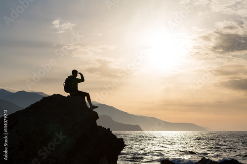 Hiking silhouette backpacker, man looking at ocean
