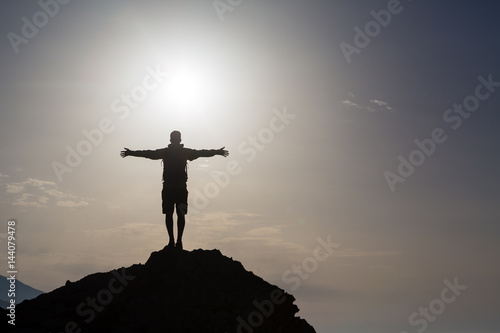 Man with arms outstretched celebrate mountains sunrise