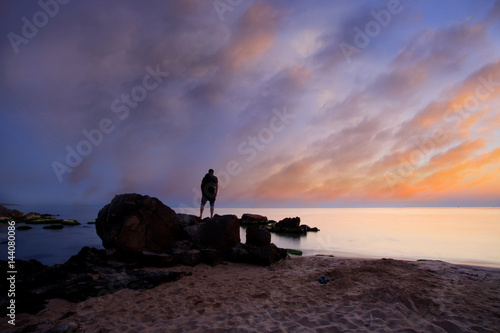 man waching calm beautiful sea sunrise with colorful dramatic clouds