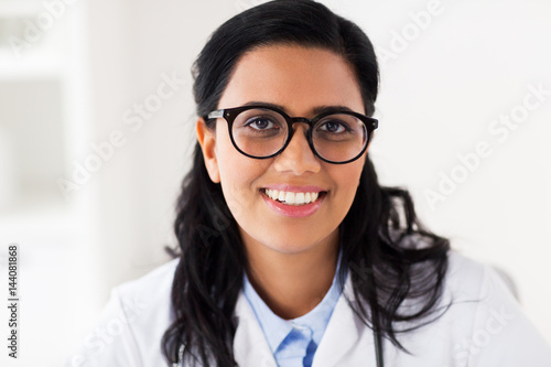 face of happy smiling young doctor in glasses