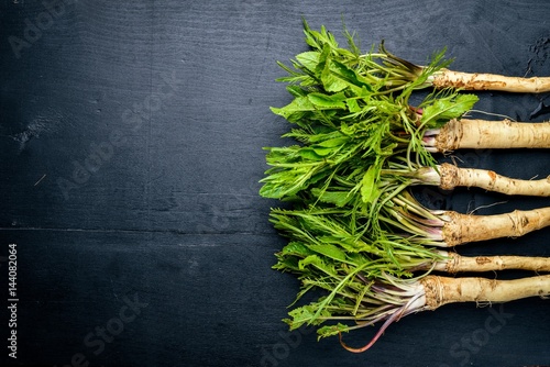 Fresh horseradish. On the black Wooden desk. Top view. photo