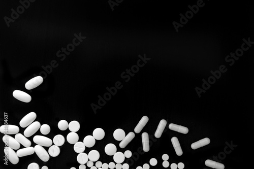Bunch of various white pills on black background