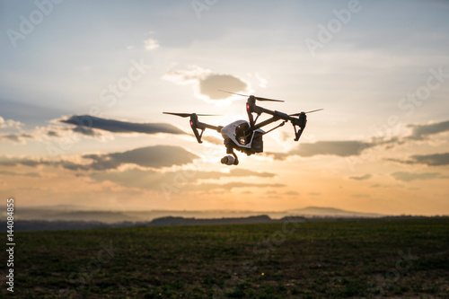 quadrocopter drone with remote control. Dark silhouette against colorfull sunset.