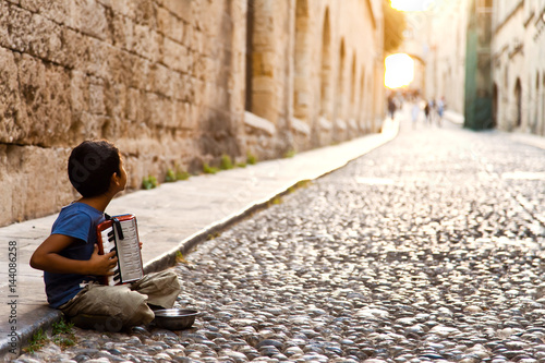 Fototapeta Naklejka Na Ścianę i Meble -  Refugee from the Middle East on the street of European city. Focus on the boy