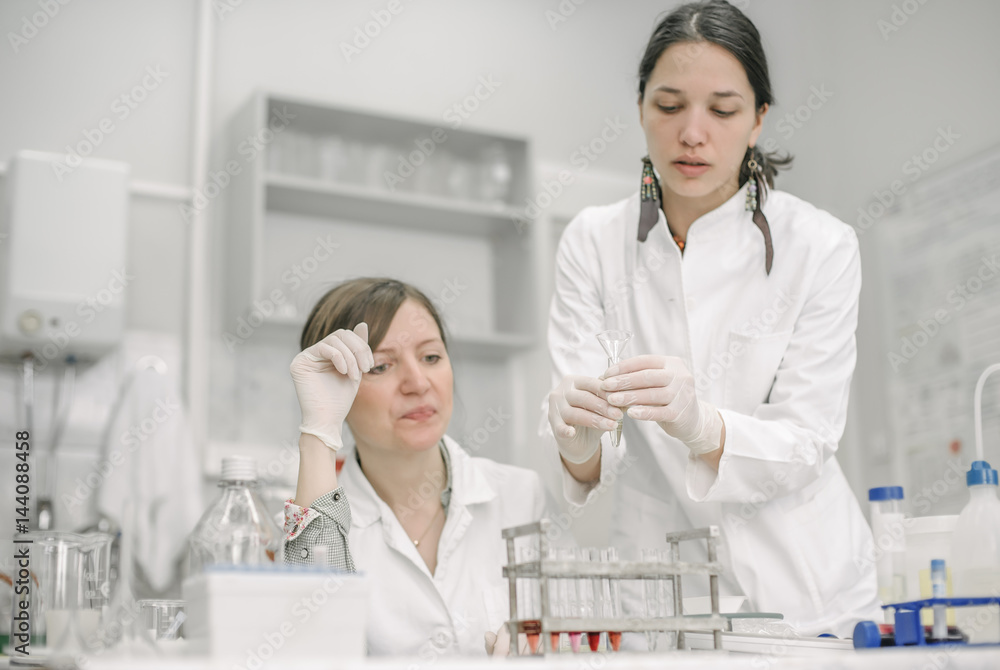 Two scientists holding a test tube with sample Two scientists holding a test tube with sample