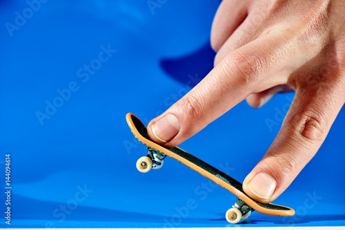 Принти на полотні Men's fingers are doing the trick on fingerbone on a blue background closeup