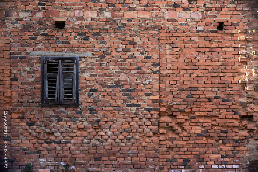 Old brick wall background including a little dark window Old brick wall background including a little dark window